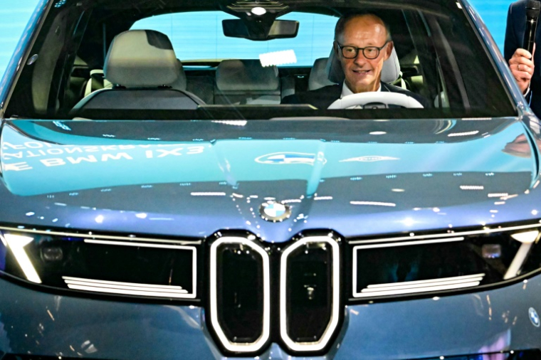 Le chancelier allemand Friedrich Merz assis dans une BMW IX3 sur le stand du constructeur automobile lors de l'ouverture du Salon international de l'automobile IAA, le 9 septembre 2025 à Munich, dans le sud de l'Allemagne The IAA Mobility fair runs from September 9 to 14, 2025. ( AFP / Tobias SCHWARZ )