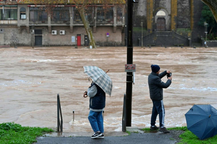Des passants dans une rue inondée à Agde après un débordement de l'Hérault provoqué par des fortes pluies, le 23 décembre 2025 dans l'Hérault ( AFP / Sylvain THOMAS )