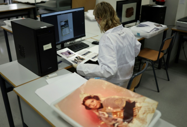 Une étudiante de l'Université des Beaux-Arts numérise des photos de famille endommagées par la boue pour les restaurer un an après les inondations à Valence, le 2 octobre 2025 en Espagne ( AFP / Thomas COEX )