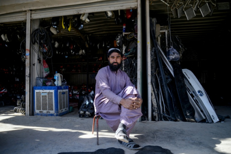 Un homme assis devant un magasin de pièces automobiles, dans un marché situé près d'un poste-frontière entre l'Afghanistan et le Pakistan, dans le district de Spin Boldak, le 29 décembre 2025 ( AFP / Sanaullah SEIAM )