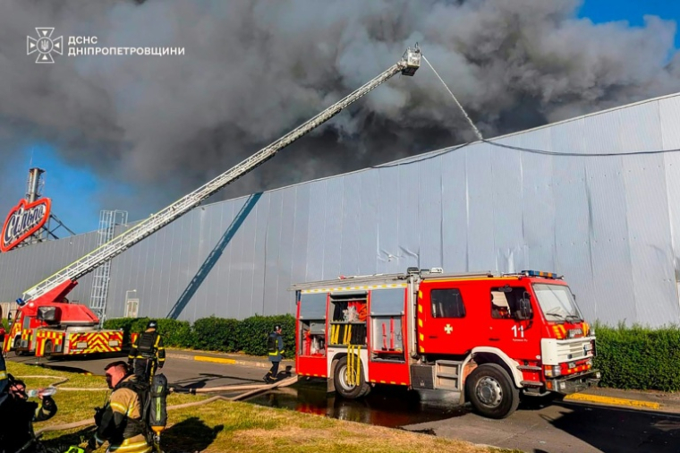 Photo diffusée par le Service d'État ukrainien pour les situations d'urgence, le 21 août 2026, montrant des pompiers luttant contre un incendie sur le site d'un centre commercial endommagé par une frappe russe à Kryvyï Rih, en Ukraine ( Service d'État ukrainien pour les situations d'urgence / Handout )