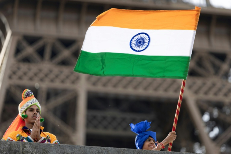Des membres de la communauté hindoue Bochasanwasi Akshar Purushottam Swaminarayan Sanstha (BAPS) agitent des drapeaux indiens lors d'une cérémonie religieuse devant la tour Eiffel, avant un défilé fluvial sur la Seine à Paris, le 3 septembre 2026 ( AFP / Kenzo TRIBOUILLARD )