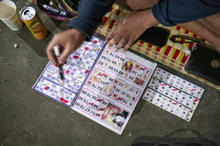 Une participante joue au bingo sur le parking d'un centre commercial désaffecté, dans le quartier de Rivière-Salée à Nouméa, en Nouvelle-Calédonie, le 8 mai 2025 ( AFP / Delphine MAYEUR )