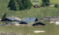 Un hélicoptère survole les maisons détruites du village de Blatten, désormais submergé, le 30 mai 2025, après l'effondrement du glacier Birch et un glissement de terrain dans les Alpes suisses ( AFP / Fabrice COFFRINI )