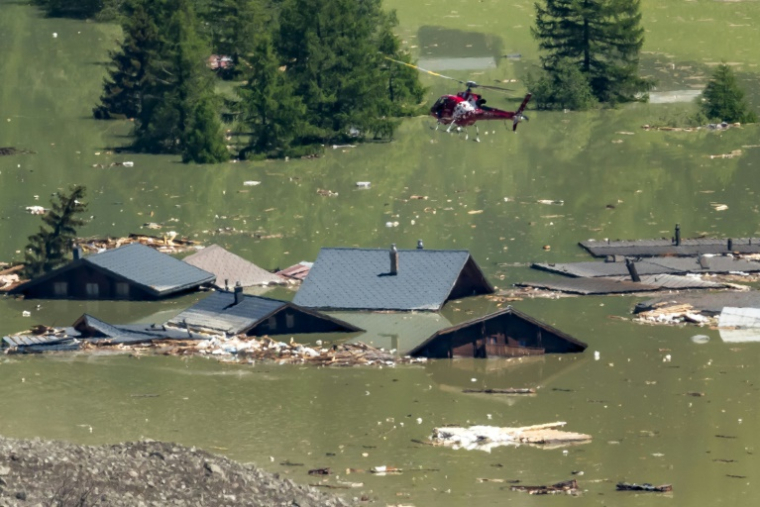 Un hélicoptère survole les maisons détruites du village de Blatten, désormais submergé, le 30 mai 2025, après l'effondrement du glacier Birch et un glissement de terrain dans les Alpes suisses ( AFP / Fabrice COFFRINI )