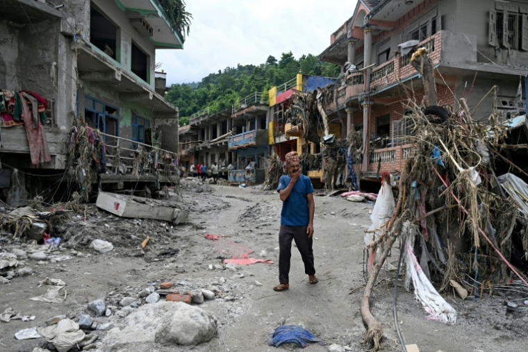 Un habitant passe devant des maisons endommagées par des crues soudaines à Devighat, dans le district de Nuwakot, le 31 août 2026 au Népal ( AFP / Arun SANKAR )