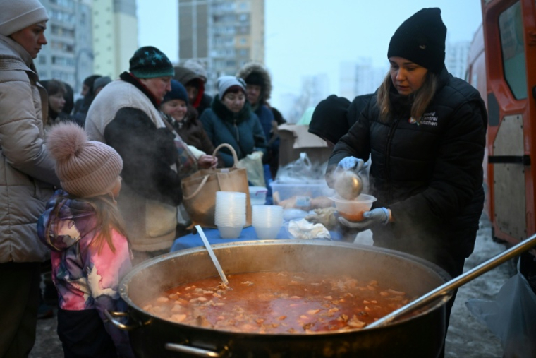 Des bénévoles de l'organisation caritative américaine World Central Kitchen distribuent un repas chaud aux habitants d'un quartier de Kiev, privé d'électricité et d'eau en raison de frappes russes, le 22 janvier 2026, en Ukraine ( AFP / Sergei GAPON )