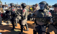 Des forces de l'ordre repoussent des manifestants devant un centre de détention pour  des familles de migrants, le 28 janvier 2026 à Dilley, au Texas ( AFP / Moisés ÁVILA )