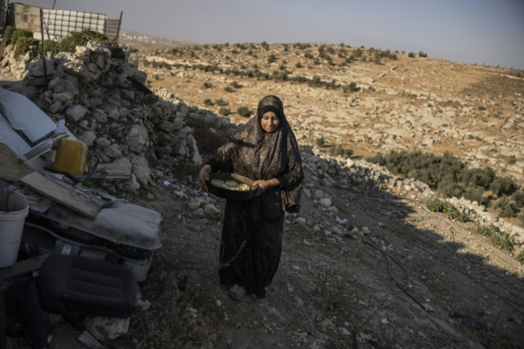 Fatma Amr transporte des gâteaux destinés à être cuits dans le four installé dans les grottes que sa famille a aménagées en habitation, dans le village d'Al-Tuwani (Cisjordanie occupée par Israël), le 11 septembre 2026 ( AFP / John WESSELS )