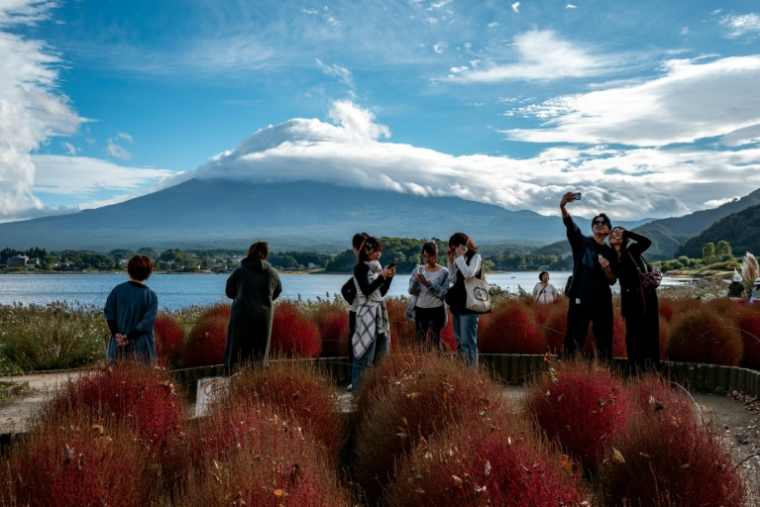 Des touristes prennent des photos devant le Mont Fuji, le 18 octobre 2025 à Fujikawaguchiko, au Japon ( AFP / Philip FONG )