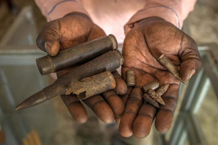 Un homme montre des balles exposées au Mémorial de Lukodi, souvenir du'un massacre perpétré dans ce village du nord de l'Ouganda en mai 2004 par la guérilla ougandaise de la l'Armée de résistance du Seigneure (LRA), le 4 septembre 2025. ( AFP / Stuart Tibaweswa )