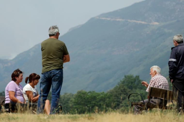 Les habitants de San Ciprian de Sanabria, dans la province de Zamora, au nord-ouest de l'Espagne, qui ont refusé d'évacuer leurs maisons, observent un incendie de forêt dans les montagnes voisines, le 21 août 2025. ( AFP / Thomas COEX )
