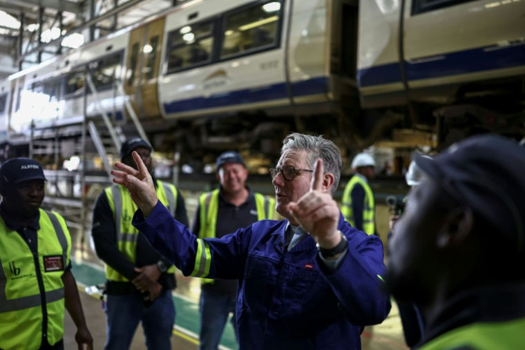 Le Premier ministre britannique Keir Starmer (2e à partir de la droite) parle à des employés dans un dépôt de trains à Johannesburg (Afrique du Sud), le 21 novembre 2025, à la veille d'un sommet du G20 dans le pays ( POOL / HENRY NICHOLLS )