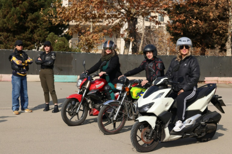 La monitrice Maryam Ghelich (g) et ses élèves Narghes (d), Elham (3e d), Leila et Mona lors d'un cours de conduite de moto dans un cente d'entraînement du nord de Téhéran, le 7 décembre 2025 en Iran ( AFP / ATTA KENARE )