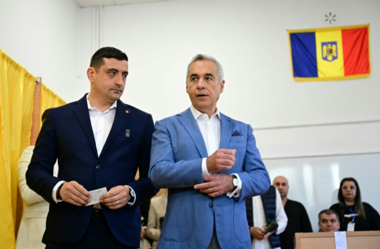 Le chef du parti nationaliste AUR et candidat à la présidentielle roumaine George Simion vote aux côtés de Calin Georgescu, exclu de la course, le 4 mai 2025 à Bucarest ( AFP / Daniel MIHAILESCU )