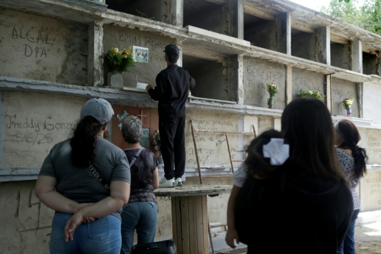 Le frère d'un homme, mort aux côtés de son épouse et de deux enfants lors du double séisme à La Guaira, dispose des fleurs dans la niche funéraire dans un cimetière de Caracas, le 29 juin 2026 ( AFP / Rosali Hernandez )