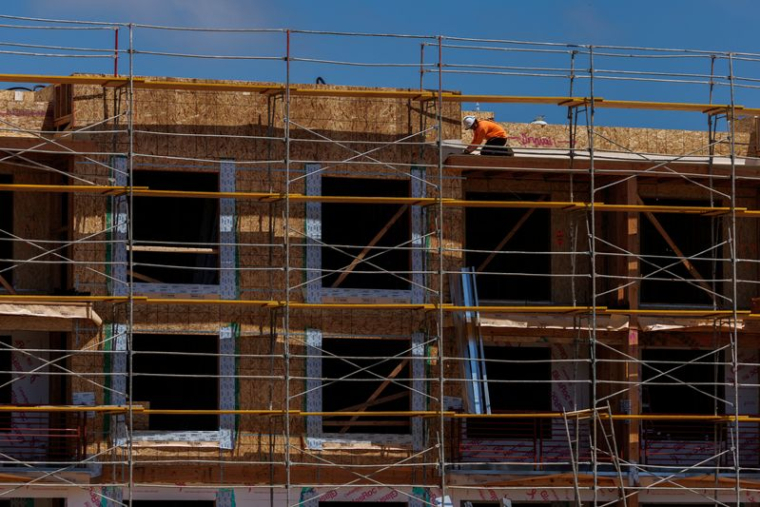 Un ouvrier du bâtiment travaille sur un projet de logements résidentiels à plusieurs unités à Encinitas, en Californie