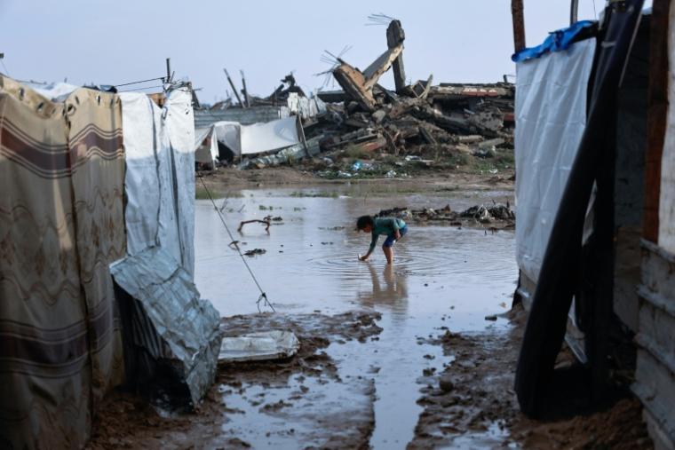 Une petite fille dans une mare d'eau, dans un camp de déplacés du quartier de Zeitoun, à Gaza-ville, inondé par la tempête Byron, le 11 décembre 2025 ( AFP / Omar AL-QATTAA )