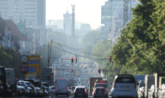 Les véhicules circulent pendant l'heure de pointe matinale, tandis que la brume de l'aube illumine la ligne d'horizon à Berlin