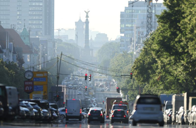 Les véhicules circulent pendant l'heure de pointe matinale, tandis que la brume de l'aube illumine la ligne d'horizon à Berlin