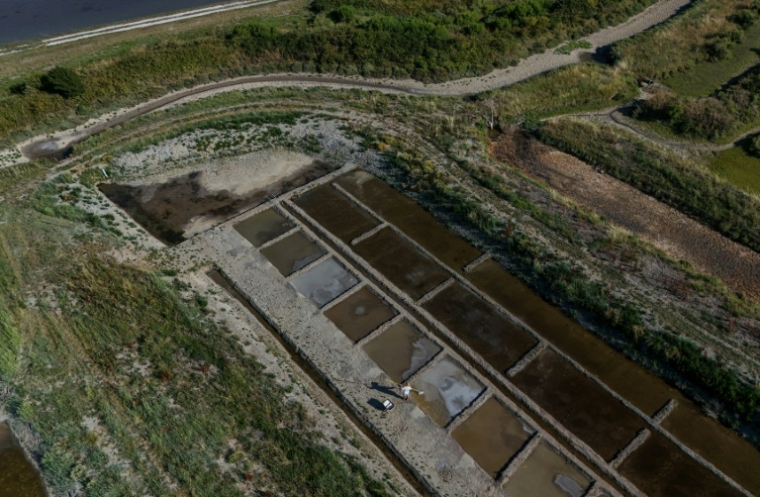 Cette photographie aérienne montre le saunier Simon Poinot récoltant la fleur de sel qui forme une fine croûte à la surface de l’eau de mer, acheminée par les bassins de son marais salant à Château-d’Oléron, sur l’île d’Oléron, dans le sud-ouest de la France, le 17 juin 2026 ( AFP / Christophe ARCHAMBAULT )