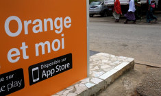 Des personnes marchent près d'un kiosque Orange money, alors qu'Orange lance ses premiers services Orange Bank à Abidjan