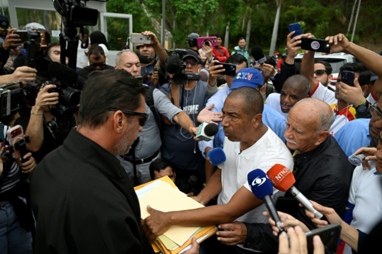 Carlos Salazar (D), coordinateur d’une coalition syndicale, remet des documents contenant des revendications à un fonctionnaire de l’ambassade des États-Unis, devant la représentation diplomatique à Caracas, le 16 avril 2026 ( AFP / Federico PARRA )