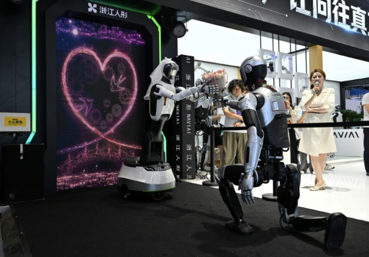Les robots humanoïdes NaviAi i3 (d) et WA2 (g), produits par Zhejiang Humanoid Robot Innovation, célèbrent une cérémonie de mariage au salon mondial des robots à Pékin, le 19 août 2026 ( AFP / ADEK BERRY )