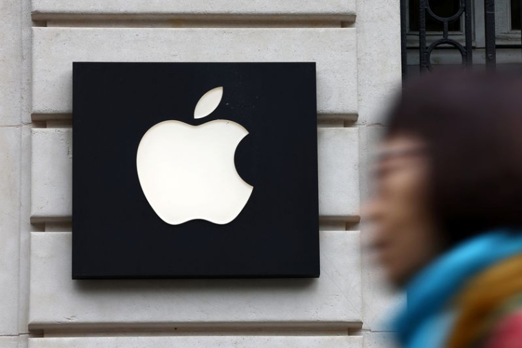 Une femme passe devant un logo Apple dans un magasin Apple à Paris