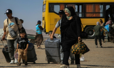 Un bus iranien dépose des réfugiés afghans prsè du poste-frontière d'Islam Qala, dans la province afghane de Hérat, le 24 juillet 2025 ( AFP / Mohsen KARIMI )