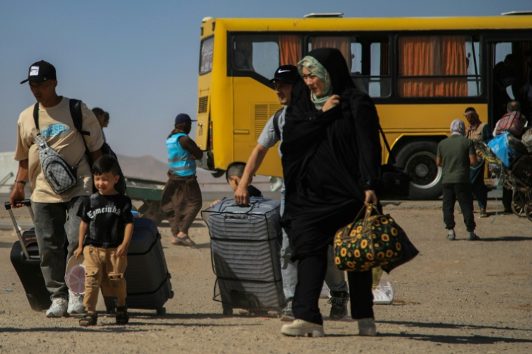 Un bus iranien dépose des réfugiés afghans prsè du poste-frontière d'Islam Qala, dans la province afghane de Hérat, le 24 juillet 2025 ( AFP / Mohsen KARIMI )
