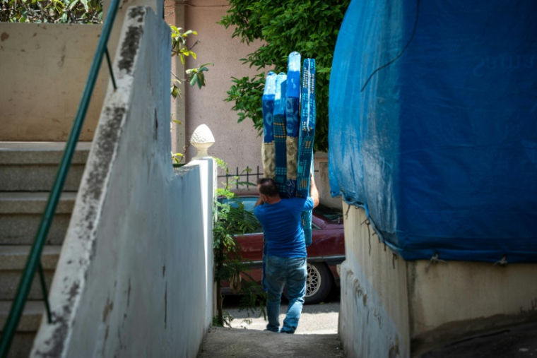 Un homme transporte des matelas devant les bâtiments de Reman, une organisation venant en aide aux travailleurs migrants à Beyrouth, le 10 mai 2026 au Liban ( AFP / Chantale SALAMEH )