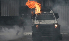Un policier antiémeute près d'un véhicule incendié à Santiago durant des affrontements entre policiers et manifestants qui participaient le 7 septembre à la marche annuelle en hommage aux victimes de la dictature instaurée au Chili par Augusto Pinochet ( AFP / RODRIGO ARANGUA )
