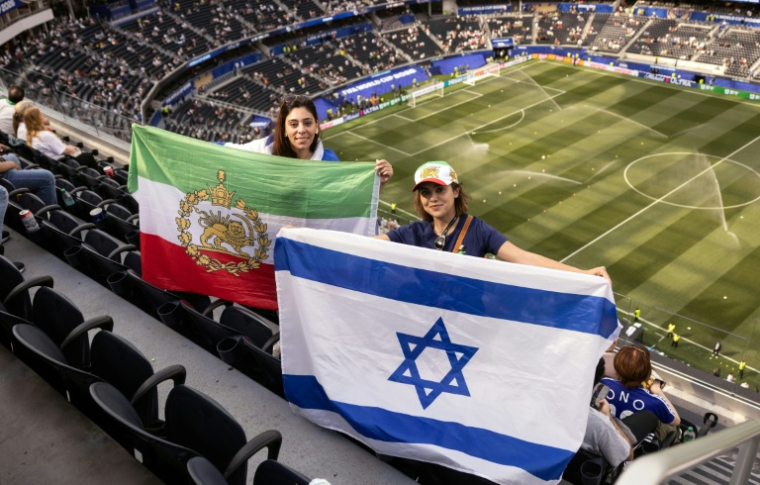 Des spectatrices assistant au match entre l'Iran et la Nouvelle-Zélande, brandissent un drapeau utilisé par l'Iran avant la révolution islamique, et un drapeau israélien, à l'intérieur du SoFi Stadium à Inglewood, près de Los Angeles, le 15 juin 2026 ( AFP / ETIENNE LAURENT )