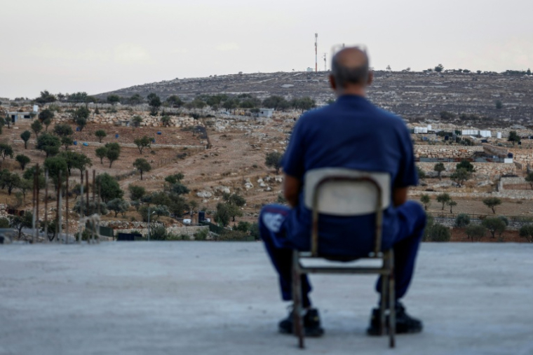 Un homme palestinien assis sur le toit de sa maison, face à un nouvel-avant poste de colons israéliens, à Burqah, en Cisjordanie, le 28 septembre 2026 ( AFP / Zain JAAFAR )