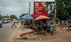 Des habitants passent le 20 août 2026 devant une affiche électorale appelant à voter lors d'un référendum constitutionnel en Guinée-Bissau. Ce référendum, organisé le 30 août par la junte au pouvoir, propose de passer à un régime présidentiel fort pour remplacer l'actuel système semi-parlementaire ( AFP / Samba BALDE )