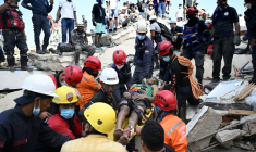 Des membres de la protection civile vénézuélienne et des pompiers sortent un jeune homme des décombres d'un immeuble effondré à Catia La Mar, dans l'Etat de La Guaira, au Venezuela, le 26 juin 2026 ( AFP / Federico PARRA )