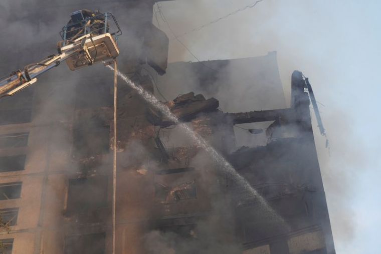 Pompiers sur le site d'un immeuble d'habitation touché par une frappe aérienne russe, à Kharkiv