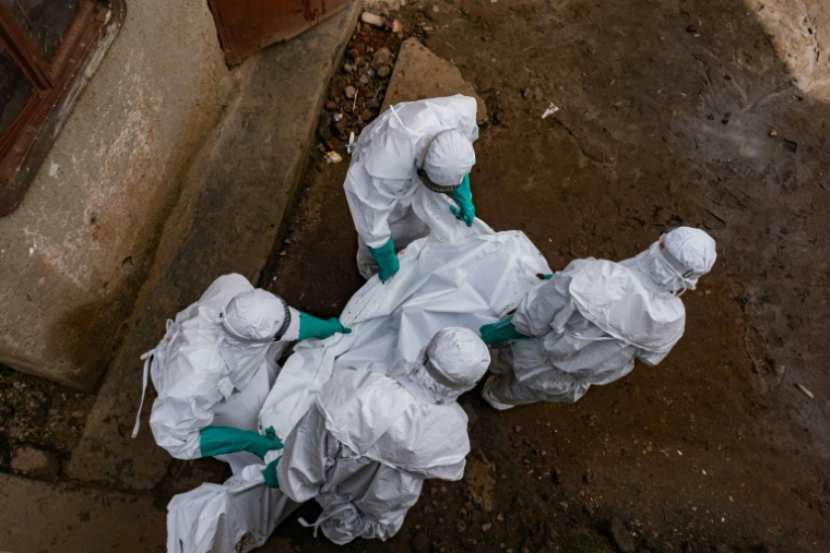 Des agents de la Croix-Rouge évacuent le corps d'une personne soupçonnée d'avoir succombé à Ebola, à Kampala, le 26 mai 2026 en Ouganda ( AFP / Badru KATUMBA )