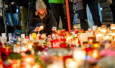 Une femme allume une bougie devant un mémorial improvisé près du lieu de l'incendie qui a ravagé un bar lors des célébrations du nouvel an dans la station de ski alpine de Crans-Montana, le 2 janvier 2026 ( AFP / MAXIME SCHMID )
