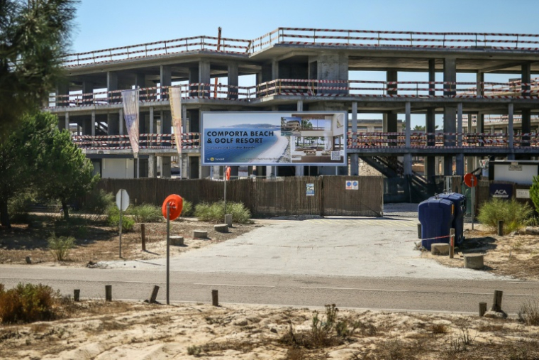 Un panneau d'affichage fait la promotion d'un "complexe de plage et de golf" devant un bâtiment en construction à Comporta,le 29 septembre 2025 au Portugal ( AFP / Patricia DE MELO MOREIRA )