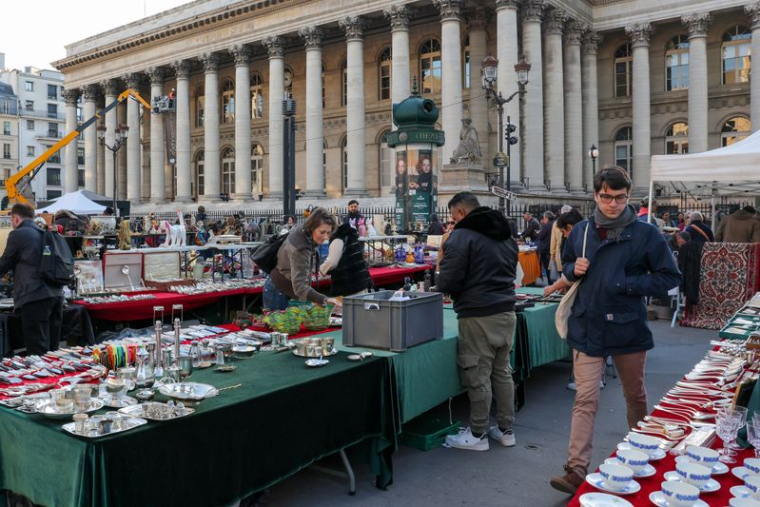 Une personne marche dans un marché devant l'ancienne Bourse de Paris