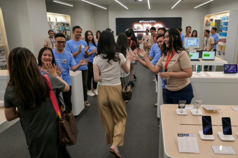 Des employés saluent des clients dans une boutique vendant l'iPhone 16 d'Apple, à Jakarta, le 11 avril 2025 en Indonésie ( AFP / BAY ISMOYO )