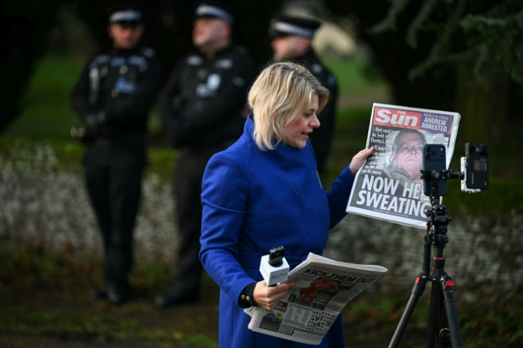 Une journaliste tient un journal avec une photo du prince déchu Andrew, devant l'entrée de Wood Farm, sur le domaine royal de Sandringham, dans le Norfolk, dans l'est de l'Angleterre, le 20 février 2026, au lendemain de son arrestation ( AFP / JUSTIN TALLIS )