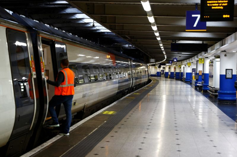 Un employé ferroviaire à côté d'un train à la gare d'Euston à Londres, en Grande-Bretagne