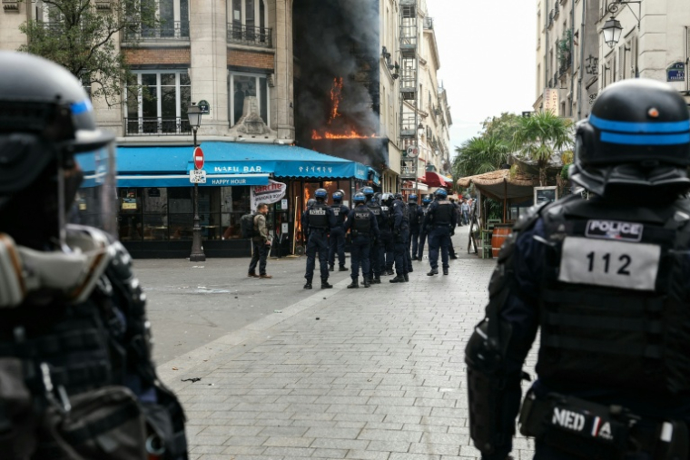 Des policiers se tiennent à côté d'un restaurant en feu lors d'une manifestation à Paris, le 10 septembre 2025 ( AFP / Alain JOCARD )