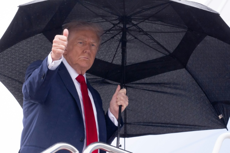 Le président américain Donald Trump tient un parapluie et lève le pouce alors qu'il monte à bord d'Air Force One avant son départ de la base aérienne d'Andrews, près de Washington, le 12 octobre 2025 ( AFP / SAUL LOEB )