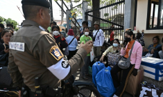 Un policier thaïlandais échange avec des personnes qui attendent de traverser le poste-frontière international de Ban Khlong Luek entre la Thaïlande et le Cambodge, dans le district d'Aranyaprathet,  en Thaïlande, le 24 juin 2025 ( AFP / Lillian SUWANRUMPHA )
