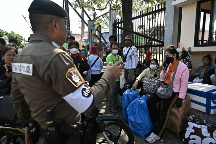 Un policier thaïlandais échange avec des personnes qui attendent de traverser le poste-frontière international de Ban Khlong Luek entre la Thaïlande et le Cambodge, dans le district d'Aranyaprathet, en Thaïlande, le 24 juin 2025 ( AFP / Lillian SUWANRUMPHA )