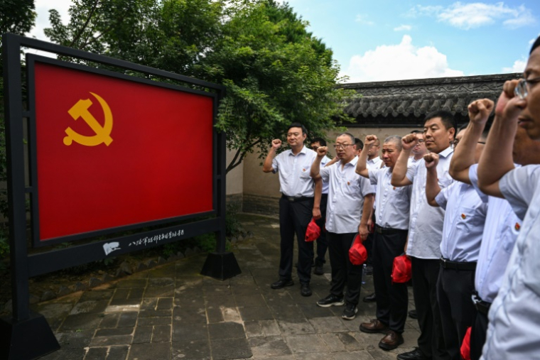 Des membres locaux prêtent serment devant un emblème du Parti communiste chinois au mémorial Wangjiayu du quartier général de l'armée de la huitième route de la guerre de résistance du peuple chinois contre l'agression japonaise à Wuxiang, dans la province du Shanxi, le 23 juillet 2025 au nord de la Chine ( AFP / Hector RETAMAL )